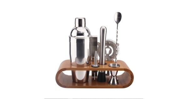 Sept accessoires à cocktail en inox rangés sur leur support en bambou