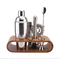 Sept accessoires à cocktail en inox rangés sur leur support en bambou