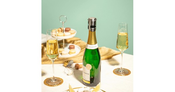Bouteille de champagne refermée avec le bouchon Vacu Vin à table