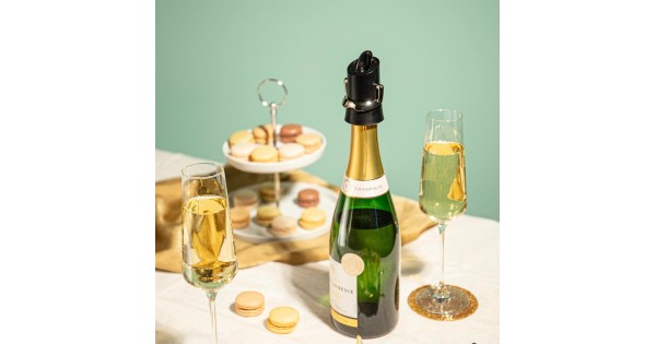 Bouchon garde-champagne Vacu Vin posé sur une bouteille à table